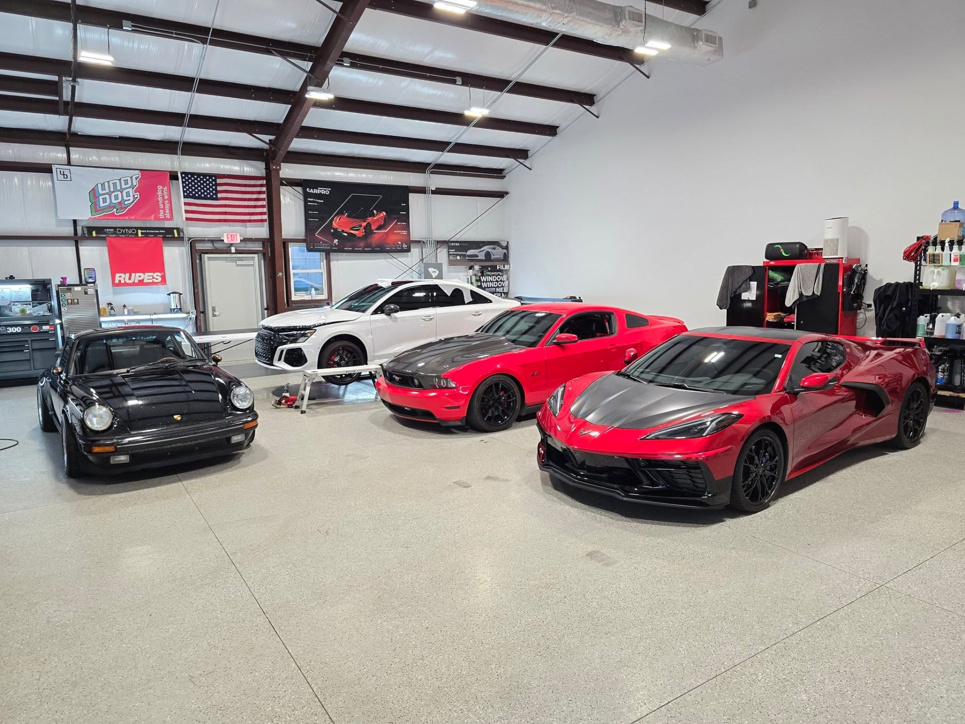 Lowcountry Detail Center shop bay with a Porsche, Audi, Mustang, and Corvette prepared for coating